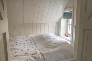 ModdergatHuisje de Eersteling的窗户客房内的一张白色床