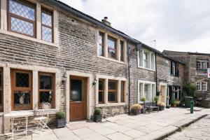 哈沃斯Stunning Blackberry Cottage with Log Burner - located on Haworth Main Street的砖砌建筑,前面设有庭院