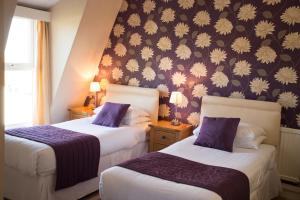 大雅茅斯福泽道恩酒店的紫色墙壁的酒店客房内的两张床