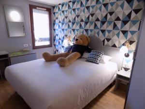 加普NESTOR HOTEL GAP et Restaurant的睡在床上的泰迪熊
