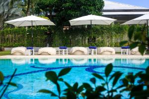 蔻立The Anda Mani Khaolak Beachfront Villas的游泳池旁设有椅子和遮阳伞