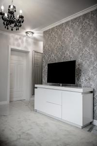 皮拉Glamour Apartments的一间客厅,客厅的白色橱柜上配有电视