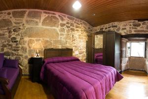 奥伦塞Casa Dos Fuelles的一间卧室配有一张紫色的床和石墙