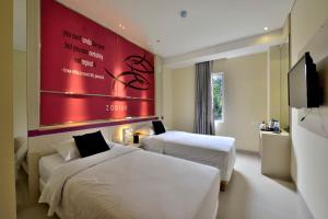 万隆Zodiak Kebon Kawung by KAGUM Hotels的酒店客房设有两张床和红色的墙壁。