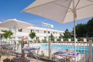 博沃诺富特尔艾敏思波罗朱里斯凡尔纳酒店的游泳池旁带桌子和遮阳伞的天井