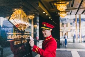 香港Mandarin Oriental, Hong Kong的身着红色制服的人站在风扇旁边