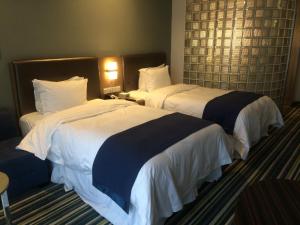 都江堰都江堰古城智选假日酒店的配有2张床铺的酒店客房,配有白色和蓝色的床单