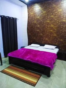 范兰德凡Radha Krishna Dham的一间卧室配有一张带紫色毯子的床