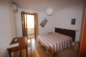 阿尔盖罗巴拜齐米酒店的一间卧室配有一张床、一张桌子和一张书桌