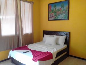 别霍港Cabinas Hukats Secret Jungle的卧室配有一张白色床,墙上挂有绘画作品