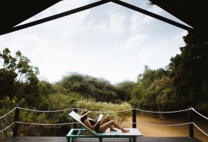雅拉Jetwing Safari Camp的两名妇女躺在吊床上,看书