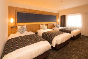 盛冈Art Hotel Morioka的一间酒店客房,房间内设有三张床