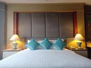 曼谷马瑞花园酒店的一间卧室配有一张带蓝色枕头的大床