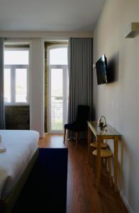 波瓦-迪瓦尔津ó Poboa Guesthouse的配有一张床和一张书桌的酒店客房