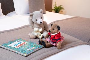 巴黎布雷迪酒店 - 巴黎火车东站的两只泰迪熊坐在书旁边的床上