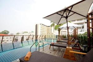 芭堤雅市中心Sunshine Hotel & Residences的游泳池畔阳台配有桌子和遮阳伞