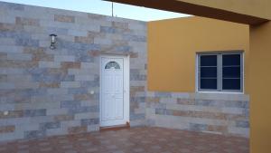 LajitaFinca Los Rosales的白色的门和砖墙上的窗户