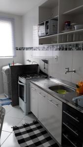 坎普斯戈伊塔卡济斯Apartamento Orquídea的白色的厨房设有水槽和炉灶。