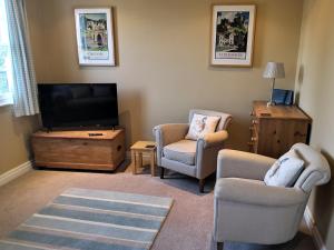 瑟斯克Duck Cottage的客厅配有2把椅子和平面电视