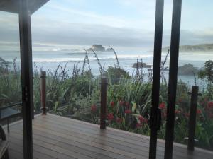 Cape FoulwindThe Bay House Beachfront Accommodation的享有大海和鲜花景致的门廊