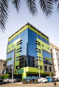 吉达Manazeli Jeddah -的一座黄色和蓝色的建筑,前面有汽车停放