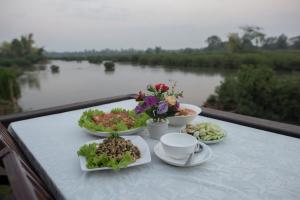 Ban KhonChanhthida Riverside Guesthouse and The River Front Restaurant的河上阳台的餐桌,上面有盘子