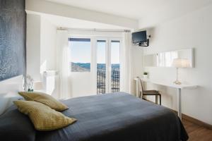 莫雷拉熙德酒店的一间卧室配有一张床、一张书桌和一个窗户。