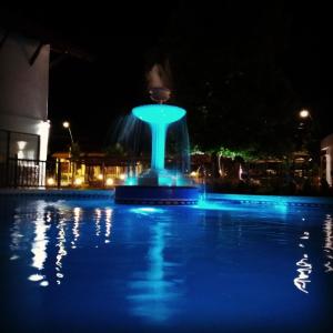 贝尔格拉诺将军镇Rancho Grande Hotel的夜晚泳池里有一个蓝色灯光喷泉