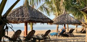 美奈Villa Mui Ne Phan Thiet SeaView的海滩上的一组椅子和遮阳伞