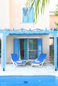 波利斯Polis Beach Village的游泳池旁的一对蓝色椅子