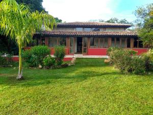 瓦尔任博尼塔Praia da Crioula的棕榈树和院子的红色房子