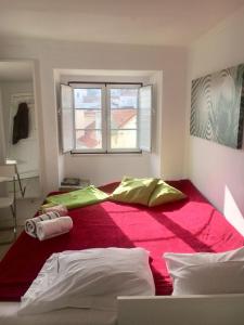 里斯本Pequeno Hostel Studio的一间卧室设有一张红色大床和窗户