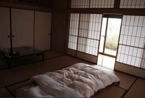 Nanakita富谷緑水庵茶道体験的一间设有床铺的卧室,位于带窗户的房间内