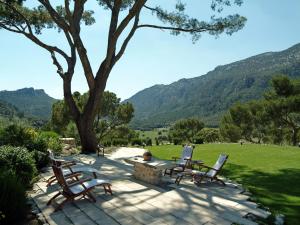奥里安特桑帕劳庄园酒店的庭院设有三把椅子、一张桌子和一棵树