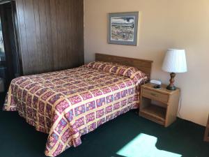柯克斯维尔乡村汽车旅馆的一间卧室配有一张床和一张带台灯的桌子