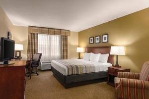 Dakota Dunes南达科他州达科他沙丘卡尔森江山旅馆的酒店客房配有一张床、一张书桌和一台电视。