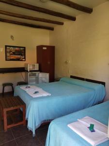 圣奥古斯汀镇posada cerro los nogales的客房设有两张床、一张桌子和一台微波炉。
