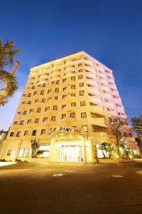 千叶幕张法米酒店的一座白色的大建筑,前面有一棵棕榈树