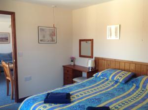 考斯Stable Cottages的一间卧室配有一张床、一张书桌和一面镜子