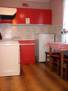 亚斯贝雷尼Lugas Szallas的厨房配有红色橱柜、桌子和冰箱