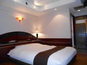 御殿场市Hotel Lumiere Gotenba (Adult Only)的一间卧室配有一张大床和木制床头板