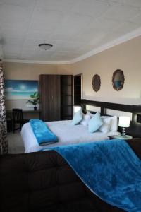 比勒陀利亚格兰查帕拉尔旅馆的一间卧室配有一张大床,上面有蓝色的毯子