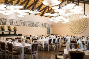 Oko SomboThe Royal Senchi Hotel and Resort的宴会厅配有白色的桌椅和吊灯