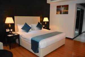 麦纳麦The Olive Hotel, Juffair的卧室配有带蓝色枕头的大型白色床