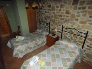 NavasfríasUn Rincón Salmantino的一间卧室设有两张床和石墙
