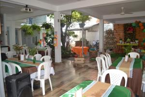 VenadilloHotel la Colina的餐厅设有桌子和带绿色桌布的白色椅子