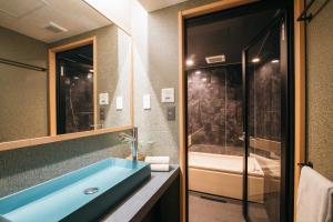 金泽Ishizue TABI-NE的浴室配有蓝色水槽和浴缸。