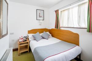 伦敦OYO Abbey Hotel, London Shepherd's Bush Market的一间卧室配有一张带木制床头板的床