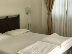 阿科Appartamenti Gardastivo的一间卧室配有两张带白色床单和桌子的床