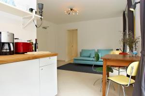 柏林拉加约斯皮公寓 - 斯皮特尔马克特米特 的厨房以及带桌子和蓝色沙发的客厅。